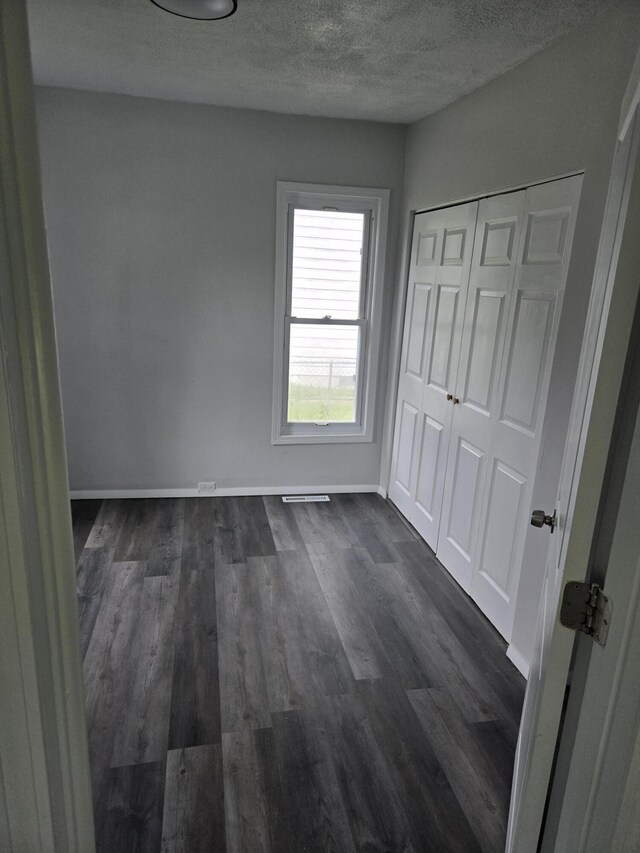 1420 Sweet St, Saginaw, MI 48602 - unfurnished bedroom with a textured ceiling, dark wood finished floors, baseboards, and a closet