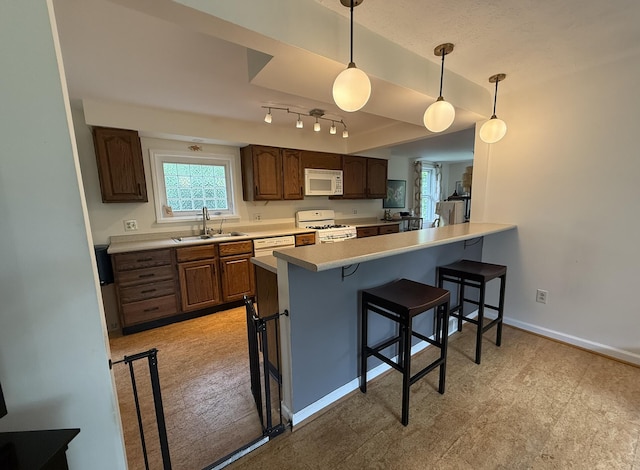 601 Cressfield Ln, Ann Arbor, MI 48103 - kitchen with white appliances, a sink, a breakfast bar, a peninsula, and baseboards