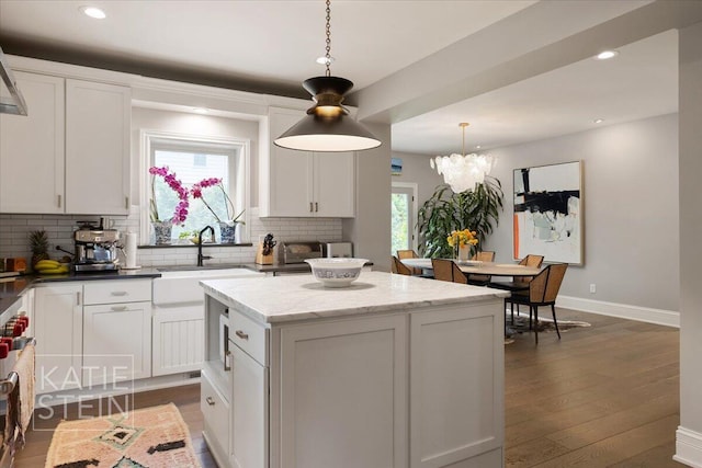 1110 Breton Rd SE, East Grand Rapids, MI 49506 - kitchen featuring decorative backsplash, dark wood-type flooring, a chandelier, a kitchen island, and white cabinets
