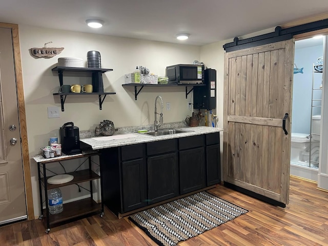 5729 N Bass Lake Rd, Irons, MI 49644 - bar with black microwave, a barn door, and wood finished floors