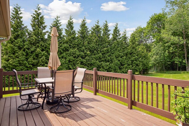 340 E 4th St, Onsted, MI 49265 - wooden deck with outdoor dining area, a lawn, and view of wooded area
