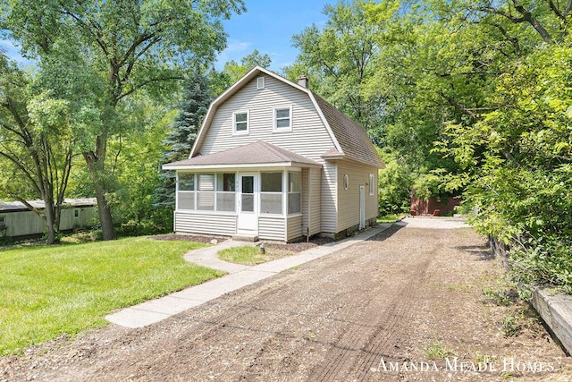 443 Nicholson St, Ionia, MI 48846 - colonial inspired home with a sunroom, roof with shingles, a gambrel roof, a front yard, and a chimney