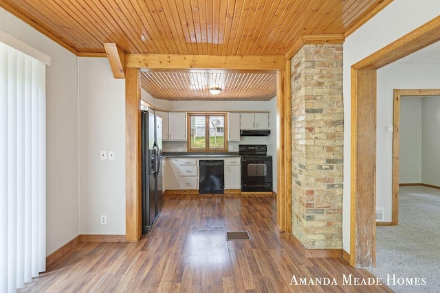 443 Nicholson St, Ionia, MI 48846 - kitchen with black appliances, dark countertops, under cabinet range hood, white cabinets, and a wood ceiling with exposed beams