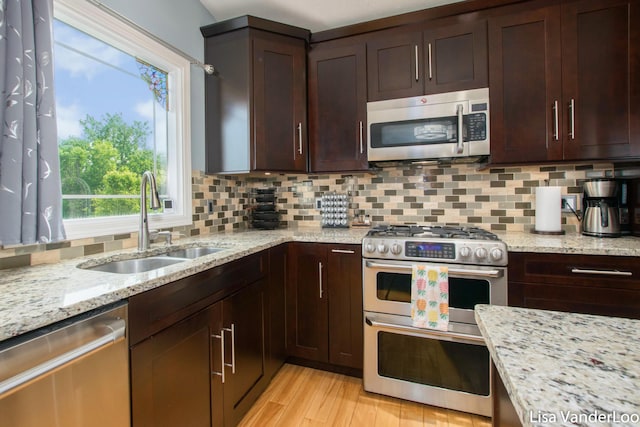 1706 Steff Ct SW, Wyoming, MI 49519 - kitchen with stainless steel appliances, tasteful backsplash, dark brown cabinetry, light stone countertops, and light wood-type flooring