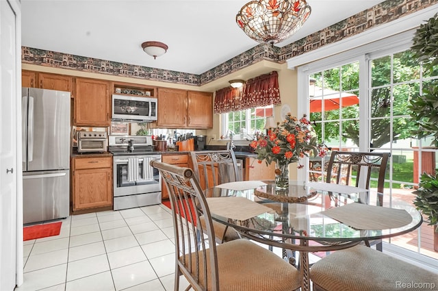 54286 Bradshaw Dr, New Baltimore, MI 48047 - kitchen featuring stainless steel appliances, dark countertops, light tile patterned flooring, and brown cabinets