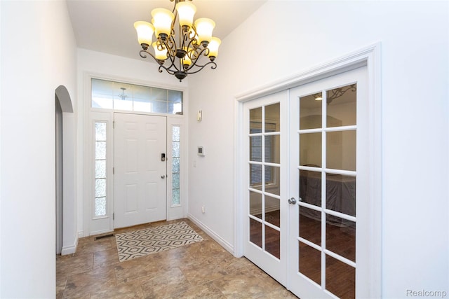 52854 Schafers Run Ct, New Baltimore, MI 48051 - entrance foyer featuring french doors, a chandelier, arched walkways, and stone finish flooring