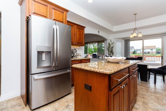 52854 Schafers Run Ct, New Baltimore, MI 48051 - kitchen with stainless steel fridge, light stone countertops, arched walkways, a center island, and brown cabinets