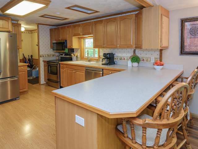 55840 Western Ave, Mattawan, MI 49071 - kitchen featuring appliances with stainless steel finishes, light countertops, a peninsula, a breakfast bar area, and light wood-type flooring
