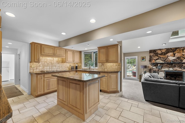 43115 Whisper Ct, Northville, MI 48168 - kitchen featuring open floor plan, freestanding refrigerator, a center island, a stone fireplace, and dark stone countertops