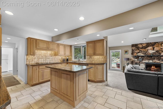 43115 Whisper Ct, Northville, MI 48168 - kitchen featuring freestanding refrigerator, open floor plan, a kitchen island, a stone fireplace, and dark stone countertops