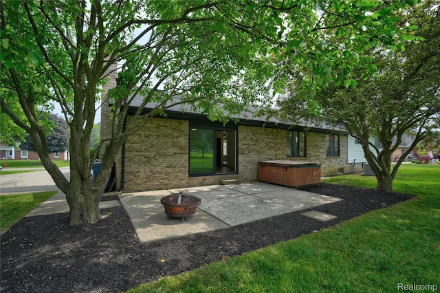 507 Charing Cross Dr, Grand Blanc, MI 48439 - rear view of property featuring a hot tub, a patio area, an outdoor fire pit, brick siding, and a lawn