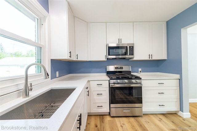 24251 Cloverlawn St, Oak Park, MI 48237 - kitchen with stainless steel appliances, white cabinets, and light wood-style floors