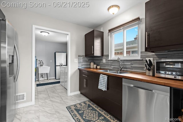 30546 Townley St, Madison Heights, MI 48071 - kitchen featuring appliances with stainless steel finishes, wood counters, light marble finish floors, washing machine and clothes dryer, and tasteful backsplash