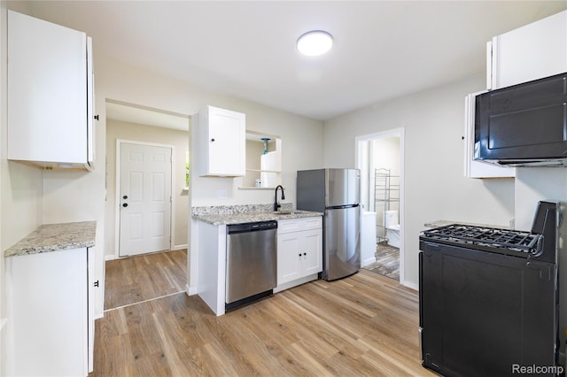 3820 17th St, Grosse Ile, MI 48192 - kitchen with black appliances, light wood-type flooring, white cabinets, and light stone countertops