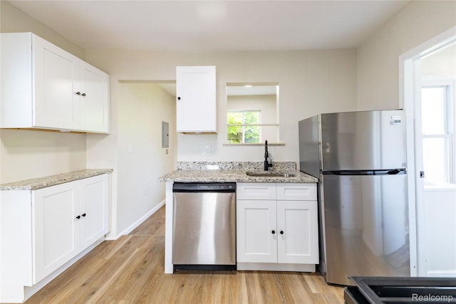 3820 17th St, Grosse Ile, MI 48192 - kitchen featuring appliances with stainless steel finishes, light wood-type flooring, white cabinets, and light stone countertops