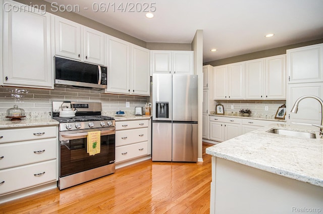 3839 Springwood Ct, Auburn Hills, MI 48326 - kitchen featuring appliances with stainless steel finishes, decorative backsplash, light wood-style floors, white cabinetry, and recessed lighting