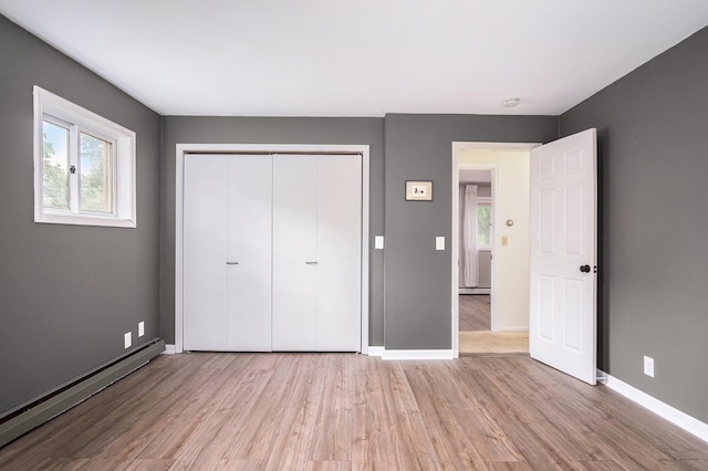 717 Novak Ln, Big Rapids, MI 49307 - unfurnished bedroom with a baseboard radiator, wood finished floors, and a closet