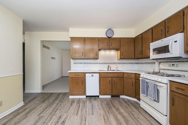 880 Andover Ct SE, Grand Rapids, MI 49508 - kitchen featuring white appliances, light countertops, light wood finished floors, backsplash, and brown cabinetry