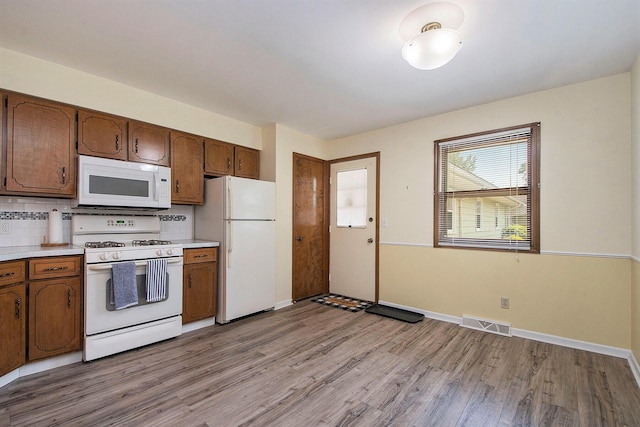 880 Andover Ct SE, Grand Rapids, MI 49508 - kitchen with white appliances, light wood finished floors, light countertops, backsplash, and brown cabinetry