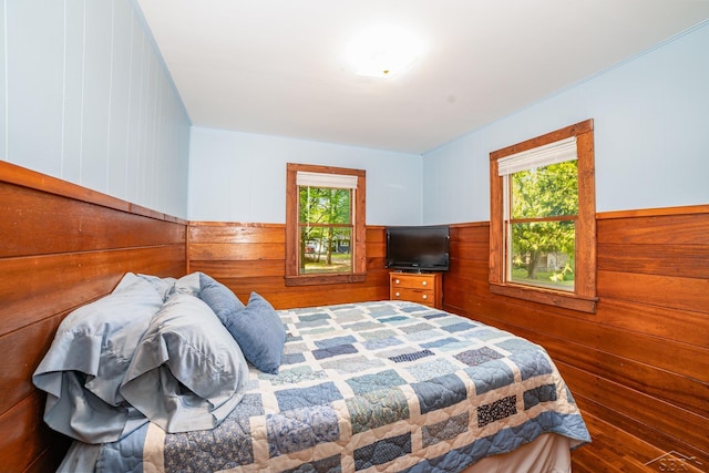441 Hillcrest Dr, Lake, MI 48632 - bedroom with wooden walls, multiple windows, and a wainscoted wall