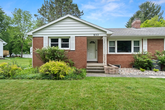 833 S Lansing St, Mason, MI 48854 - view of front of property with brick siding, a front yard, and a chimney
