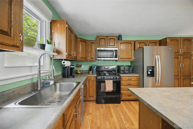 1614 Colorado St, Marysville, MI 48040 - kitchen featuring appliances with stainless steel finishes, light wood-style flooring, brown cabinets, and a textured ceiling