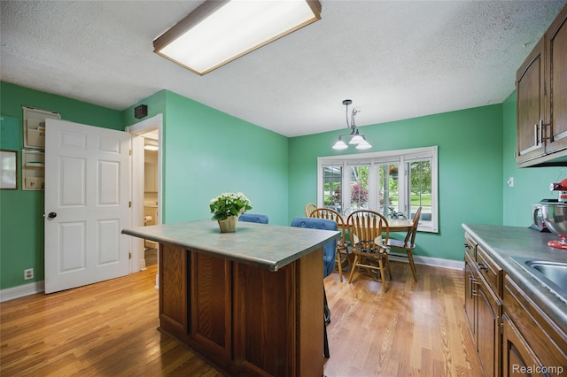 1614 Colorado St, Marysville, MI 48040 - kitchen featuring light wood-style floors, a textured ceiling, a kitchen island, and pendant lighting