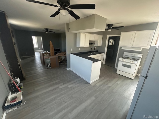 910 Monroe St, Carleton, MI 48117 - kitchen featuring white gas stove, under cabinet range hood, a ceiling fan, open floor plan, and white cabinetry