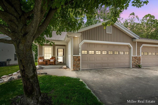 610 Riverwalk St Unit 18, Hastings, MI 49058 - view of front facade with stone siding, a garage, concrete driveway, board and batten siding, and a shingled roof
