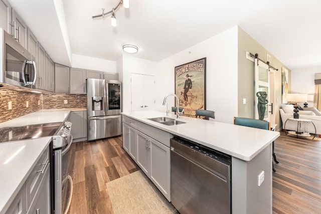 293 N 2nd St Unit 201, Brighton, MI 48116 - kitchen with stainless steel appliances, gray cabinetry, a barn door, dark wood-style flooring, and light countertops