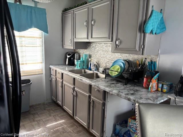 938 Barney Ave, Flint, MI 48503 - kitchen featuring gray cabinetry, freestanding refrigerator, decorative backsplash, and light countertops