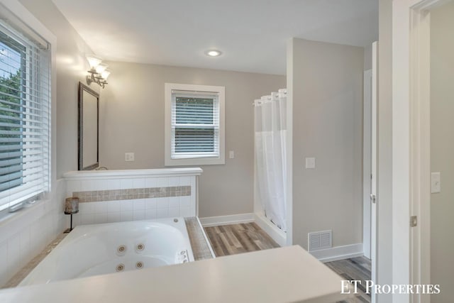 12150 W Devis Rd, West Olive, MI 49460 - full bath with healthy amount of natural light, a tub with jets, wood finished floors, and recessed lighting