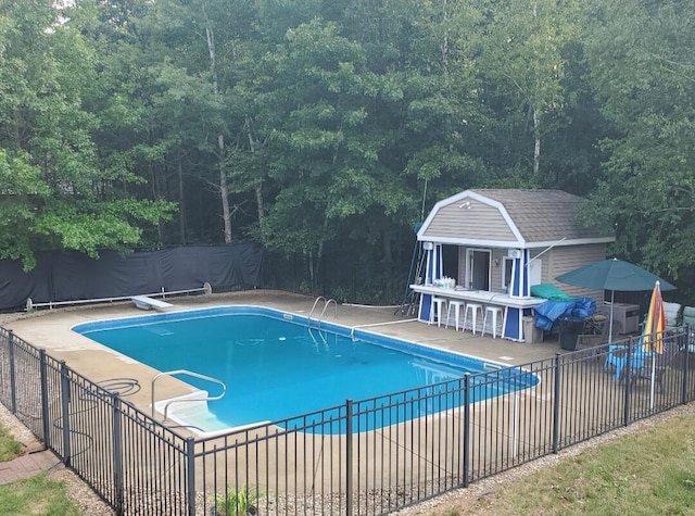 12150 W Devis Rd, West Olive, MI 49460 - view of pool featuring an outdoor structure, a patio area, a view of trees, and a diving board