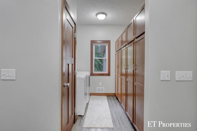 12150 W Devis Rd, West Olive, MI 49460 - hall featuring washing machine and dryer, light wood-type flooring, and a textured ceiling
