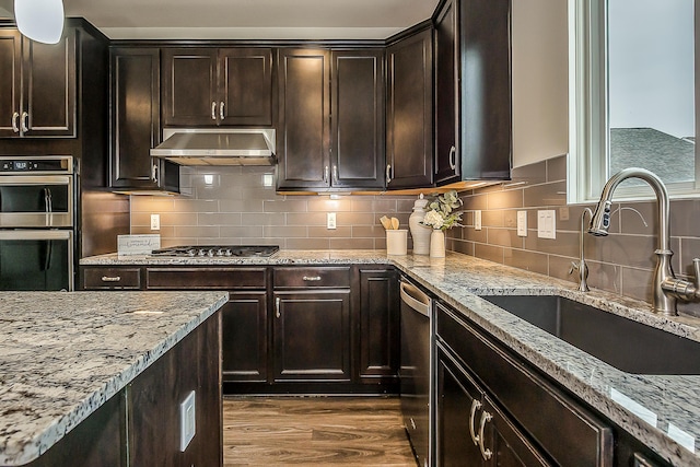 2767 St Regis Way, Ann Arbor, MI 48105 - kitchen with stainless steel appliances, ventilation hood, light stone counters, dark wood-type flooring, and decorative backsplash