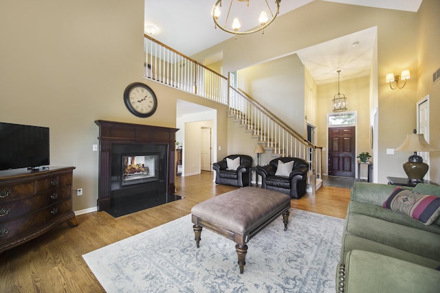 712 Dornoch Dr, Ann Arbor, MI 48103 - living room featuring a towering ceiling, a chandelier, wood finished floors, stairs, and a multi sided fireplace