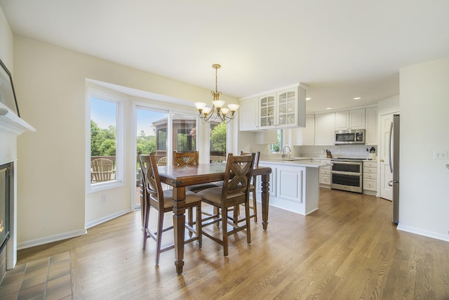 712 Dornoch Dr, Ann Arbor, MI 48103 - dining area featuring a chandelier, healthy amount of natural light, wood finished floors, recessed lighting, and a glass covered fireplace