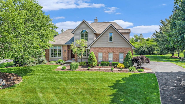 712 Dornoch Dr, Ann Arbor, MI 48103 - traditional-style home featuring brick siding, a front yard, a shingled roof, and a chimney