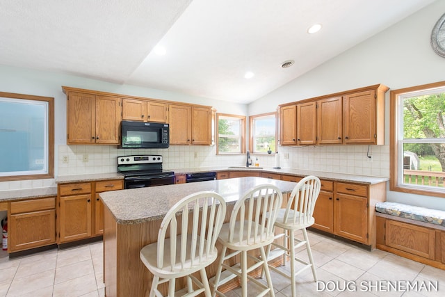 3747 Leonard St NW, Grand Rapids, MI 49534 - kitchen featuring black appliances, lofted ceiling, light countertops, a center island, and light tile patterned flooring