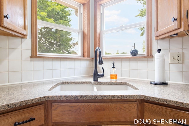 3747 Leonard St NW, Grand Rapids, MI 49534 - kitchen view of tasteful backsplash, light stone counters, and brown cabinetry