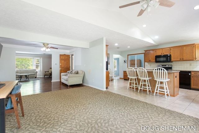 3747 Leonard St NW, Grand Rapids, MI 49534 - kitchen featuring black appliances, a ceiling fan, open floor plan, a kitchen breakfast bar, and lofted ceiling