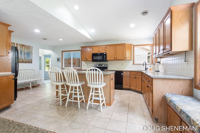 3747 Leonard St NW, Grand Rapids, MI 49534 - kitchen featuring black appliances, tasteful backsplash, a kitchen breakfast bar, a center island, and light tile patterned floors