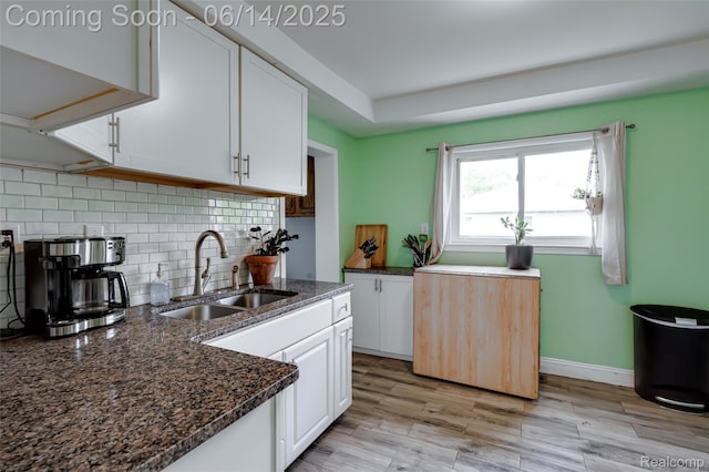 1217 E Madge Ave, Hazel Park, MI 48030 - kitchen with white cabinets, decorative backsplash, dark stone countertops, light wood-style flooring, and a tray ceiling