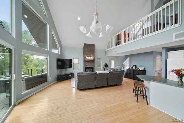 13832 Grandview Dr, Cement City, MI 49233 - living room with high vaulted ceiling, a chandelier, light wood-type flooring, healthy amount of natural light, and a stone fireplace