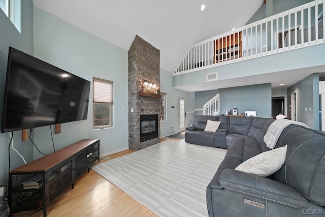13832 Grandview Dr, Cement City, MI 49233 - living area featuring high vaulted ceiling, hardwood / wood-style floors, a stone fireplace, and stairway