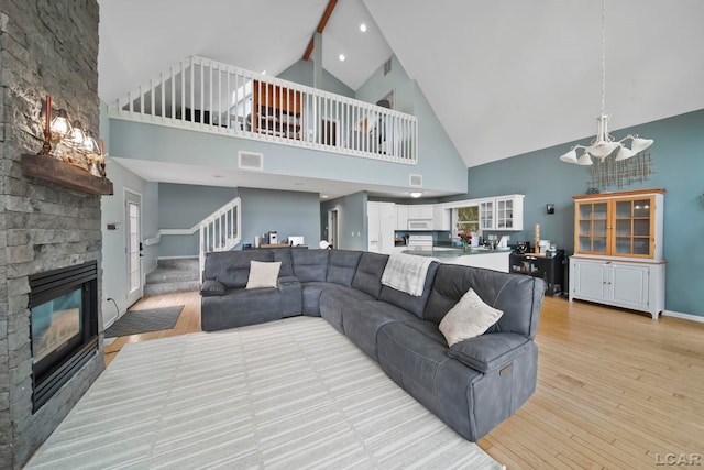 13832 Grandview Dr, Cement City, MI 49233 - living area featuring high vaulted ceiling, a fireplace, stairs, light wood finished floors, and a chandelier