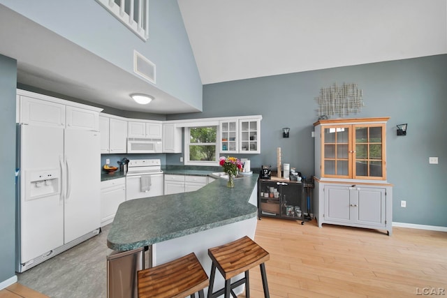 13832 Grandview Dr, Cement City, MI 49233 - kitchen featuring white appliances, dark countertops, high vaulted ceiling, white cabinets, and a breakfast bar area