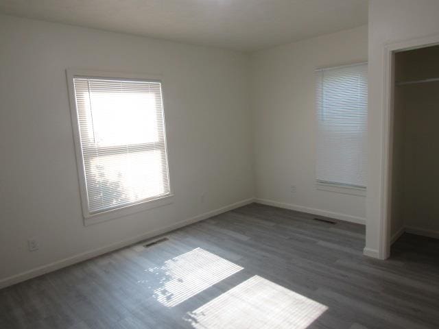 516 Cedar St, Owosso, MI 48867 - unfurnished bedroom featuring multiple windows, wood finished floors, and a closet