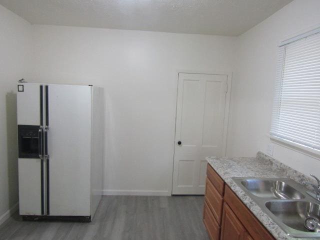 516 Cedar St, Owosso, MI 48867 - kitchen with white refrigerator with ice dispenser, wood finished floors, brown cabinets, and light countertops