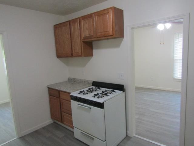 516 Cedar St, Owosso, MI 48867 - kitchen featuring white gas range, wood finished floors, brown cabinets, and light countertops